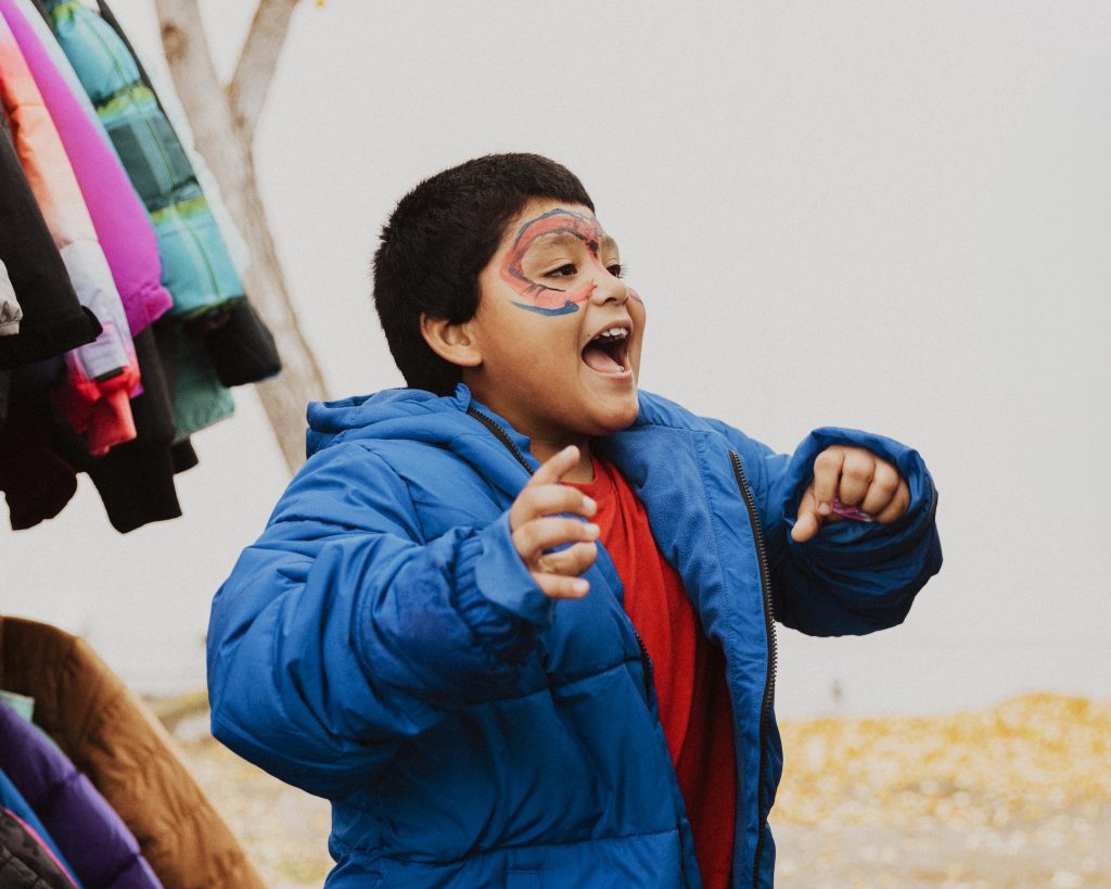 A boy with face paint shows off his new blue coat