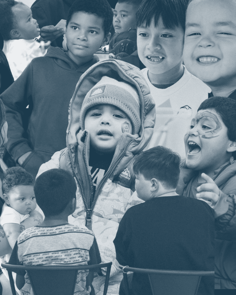 A collage of diverse children, some smiling, some serious, and some facing away from the camera. One child in front wears a hooded coat and beanie. The image is in blueish grayscale tones.